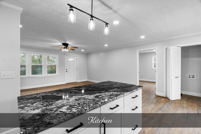 kitchen featuring decorative light fixtures, white cabinetry, ceiling fan, wood finished floors, and dark stone counters