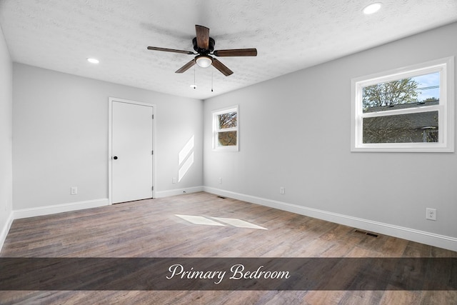 spare room with a textured ceiling, ceiling fan, recessed lighting, wood finished floors, and baseboards