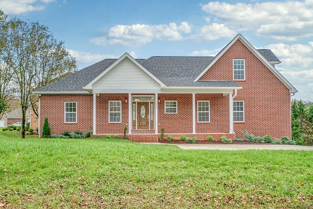 view of front of property featuring brick siding, a front lawn, and roof with shingles