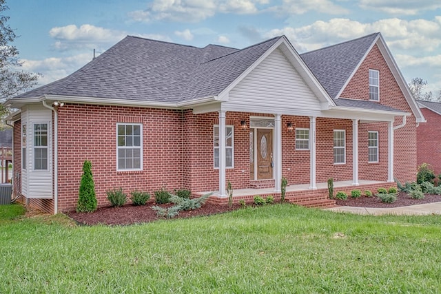 view of front facade with a shingled roof, brick siding, and a front lawn