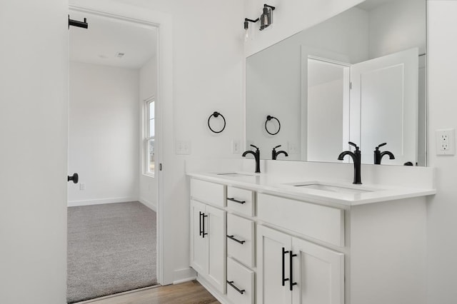 bathroom with double vanity, a sink, and baseboards