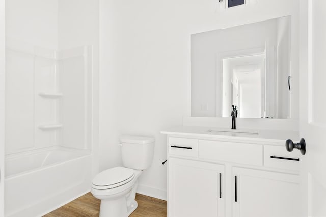 bathroom with baseboards, toilet, wood finished floors,  shower combination, and vanity