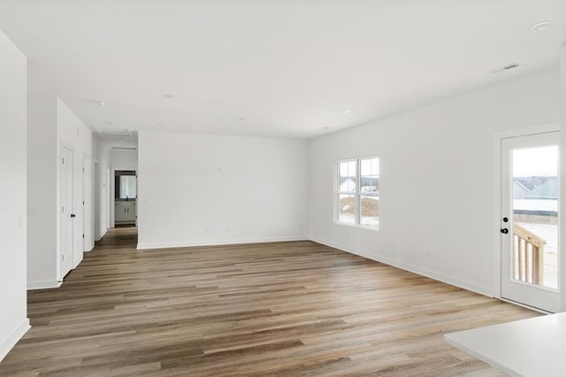 unfurnished living room with baseboards, visible vents, and light wood-style floors