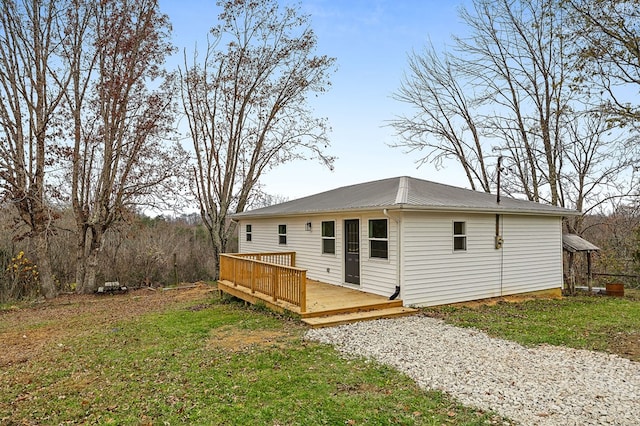 back of property featuring a yard, metal roof, driveway, and a wooden deck