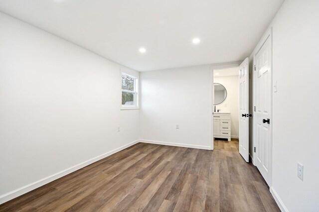 unfurnished bedroom featuring dark wood-type flooring, recessed lighting, connected bathroom, and baseboards