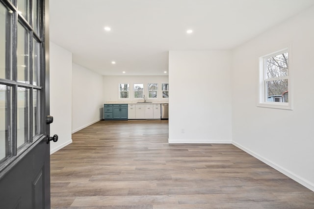 unfurnished living room featuring light wood-style floors, recessed lighting, a sink, and baseboards