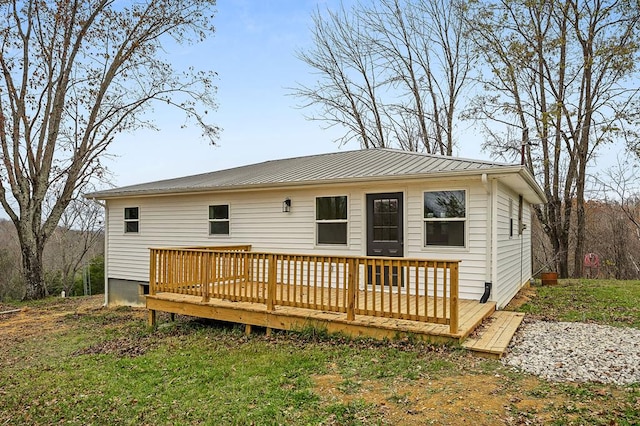 rear view of house featuring a deck, metal roof, and a lawn