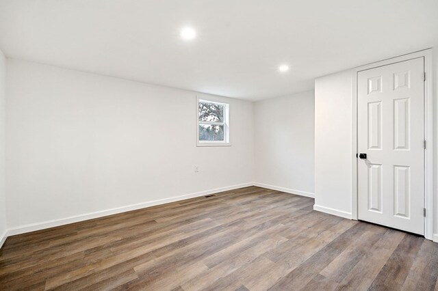 empty room featuring baseboards, wood finished floors, and recessed lighting