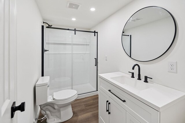 bathroom featuring visible vents, toilet, a shower stall, vanity, and wood finished floors