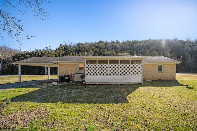 back of house featuring a yard, brick siding, and a sunroom