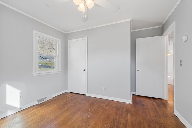 unfurnished bedroom featuring visible vents, crown molding, baseboards, wood finished floors, and a closet