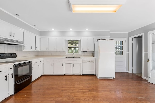 kitchen featuring under cabinet range hood, a sink, wood finished floors, white appliances, and light countertops