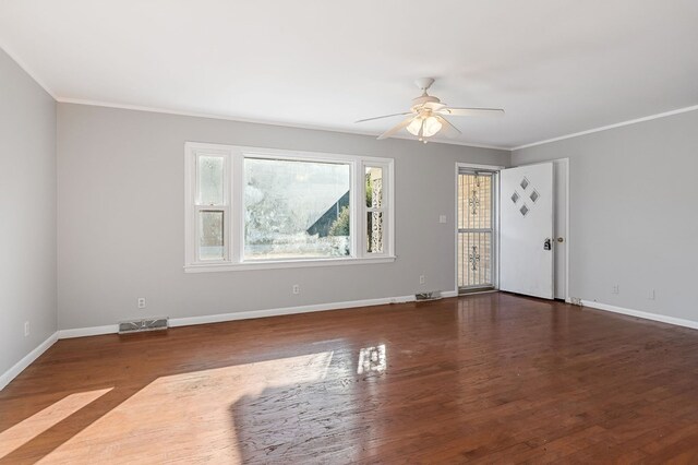 empty room with visible vents, baseboards, wood finished floors, and ornamental molding