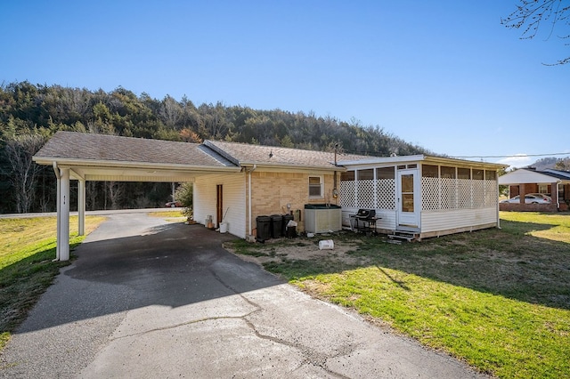 view of front of property with cooling unit, a carport, a front lawn, aphalt driveway, and brick siding