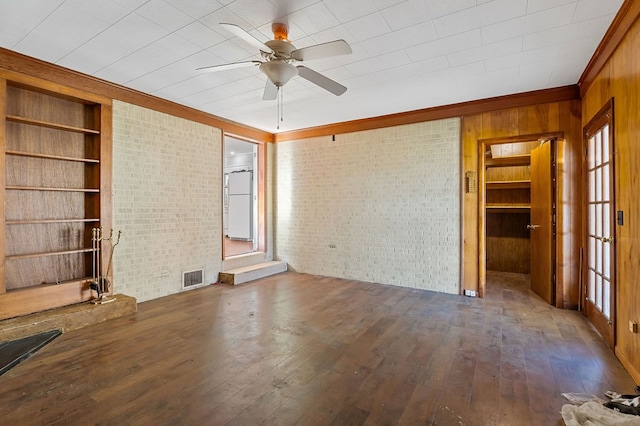 unfurnished living room with visible vents, built in features, brick wall, and wood-type flooring