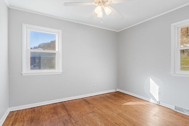 unfurnished room featuring visible vents, a healthy amount of sunlight, crown molding, and wood finished floors