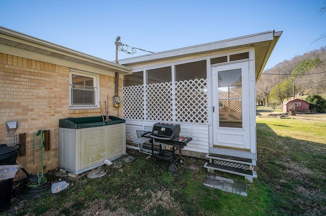 exterior space featuring a lawn, brick siding, and a sunroom