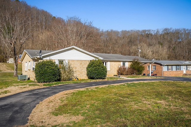 ranch-style house with cooling unit, driveway, brick siding, and a front yard