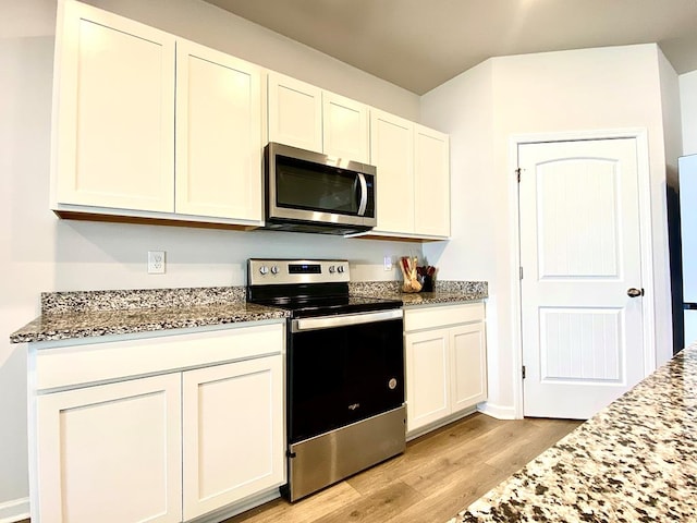 kitchen featuring white cabinetry, stone counters, light wood-style flooring, and appliances with stainless steel finishes