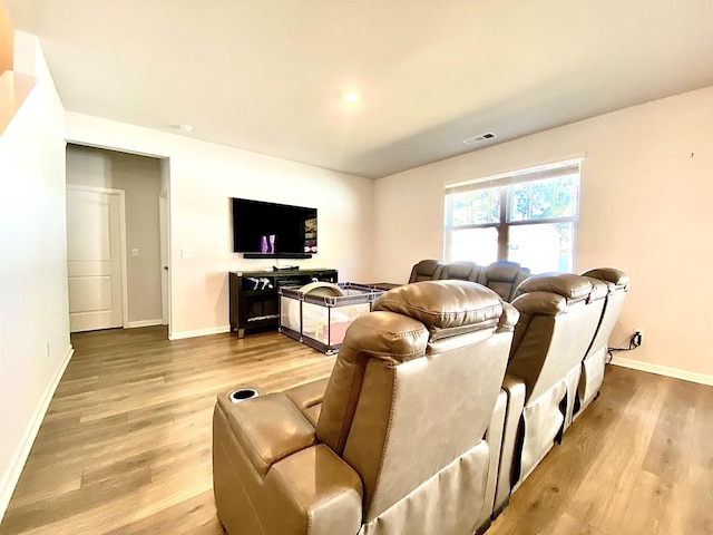 living room featuring light wood-type flooring, visible vents, and baseboards