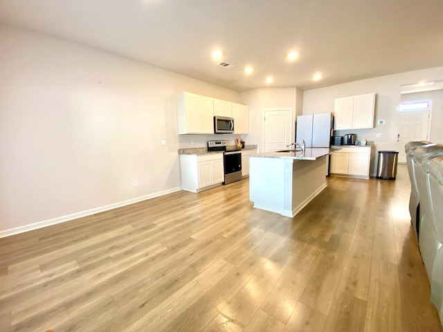 kitchen featuring stainless steel appliances, visible vents, light wood-style floors, open floor plan, and baseboards