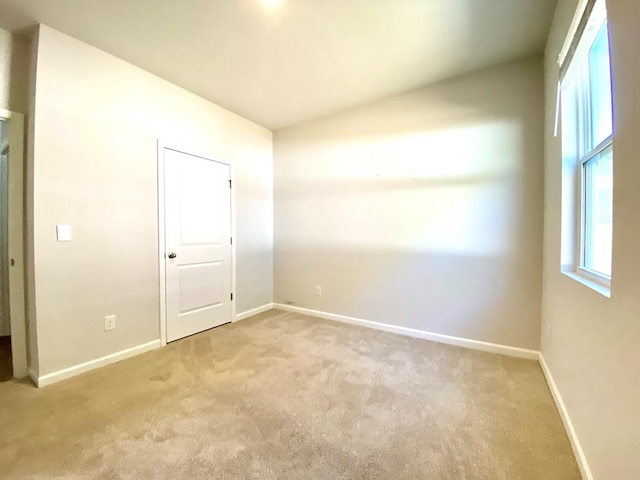 spare room featuring lofted ceiling, carpet floors, and baseboards