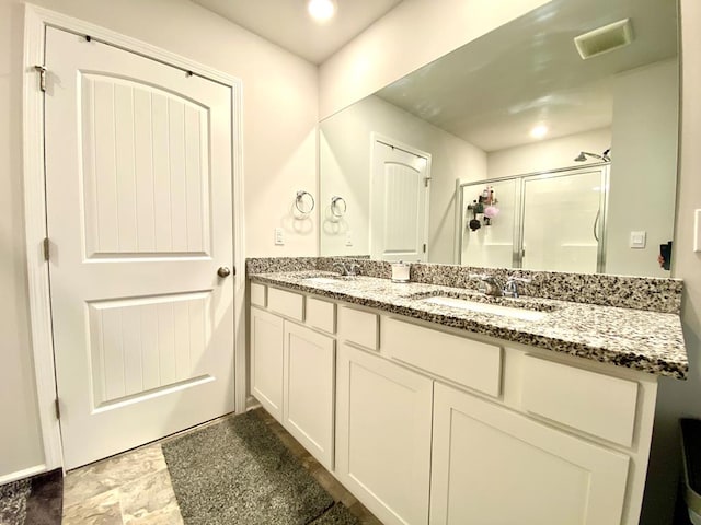 bathroom featuring a stall shower, visible vents, a sink, and double vanity