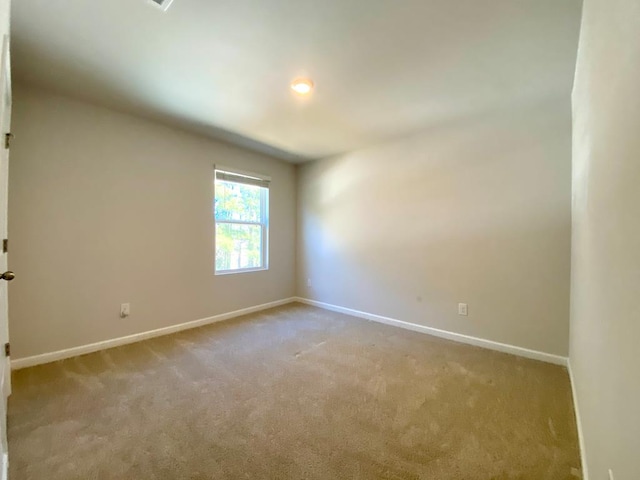 carpeted empty room featuring baseboards