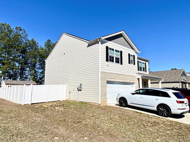 view of home's exterior featuring driveway, an attached garage, fence, and brick siding