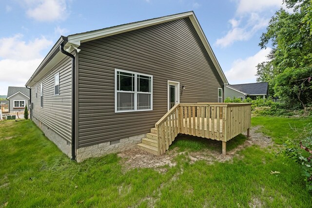 rear view of property with crawl space, a wooden deck, and a yard