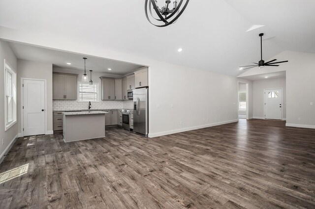 kitchen with stainless steel appliances, light countertops, gray cabinetry, open floor plan, and a kitchen island