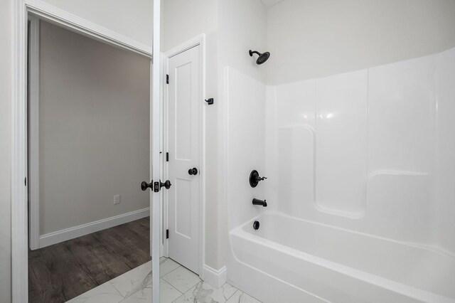 full bath with shower / washtub combination, marble finish floor, and baseboards