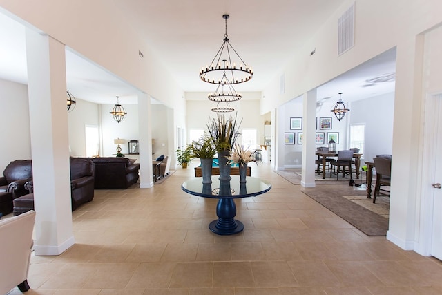 hall featuring light tile patterned floors, baseboards, visible vents, and a notable chandelier