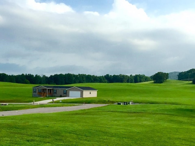 view of property's community featuring view of golf course, a lawn, and an attached garage