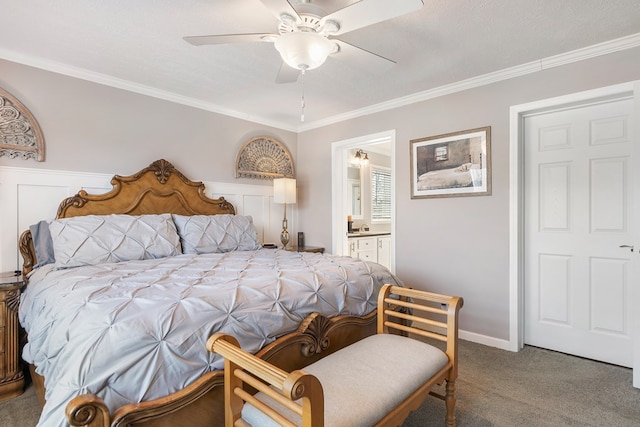 carpeted bedroom with ensuite bath, crown molding, and a ceiling fan