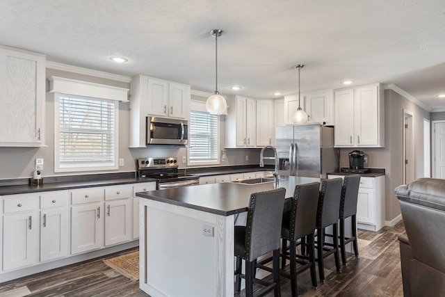 kitchen featuring a sink, dark countertops, stainless steel appliances, white cabinets, and crown molding