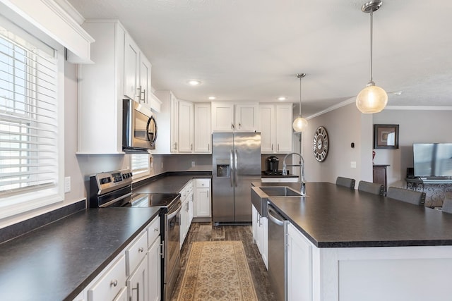 kitchen featuring dark countertops, crown molding, dark wood-type flooring, stainless steel appliances, and a sink