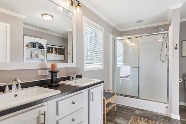 bathroom with a sink, a shower with shower door, wood finished floors, and crown molding