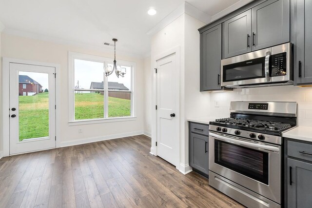 living area featuring wood finished floors, visible vents, a ceiling fan, ornamental molding, and a brick fireplace