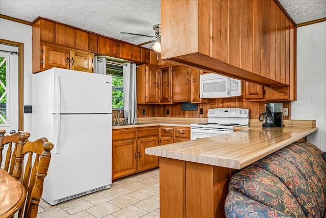 kitchen featuring white appliances, brown cabinets, a peninsula, and a textured ceiling