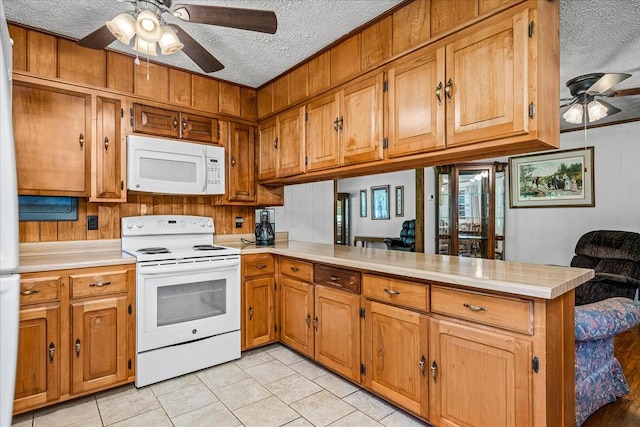 kitchen with a peninsula, white appliances, ceiling fan, and light countertops