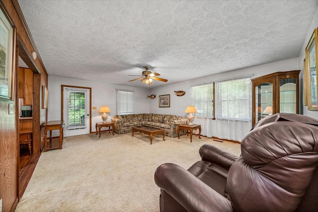 living room with ceiling fan, a textured ceiling, and carpet flooring