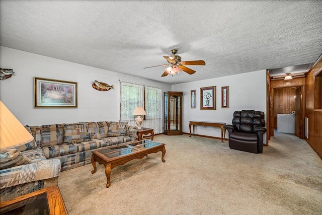 living area with ceiling fan, a textured ceiling, baseboards, and light colored carpet