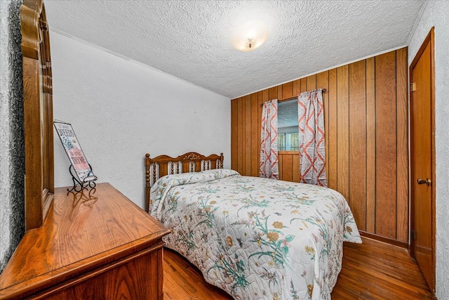 bedroom featuring a textured ceiling, dark wood-type flooring, and wood walls