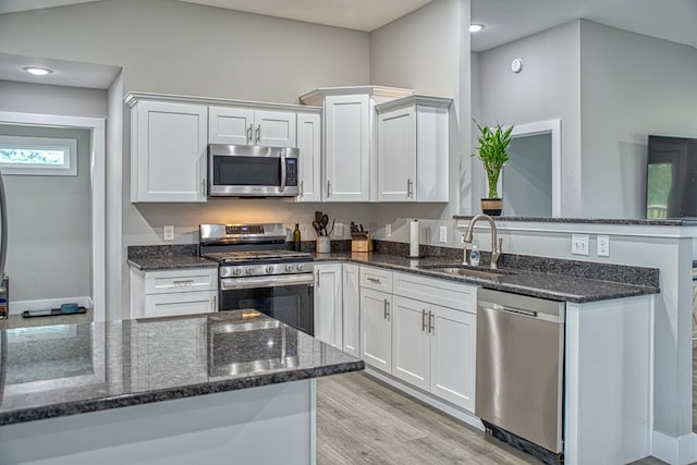 kitchen with white cabinetry, light wood-style flooring, a sink, and appliances with stainless steel finishes