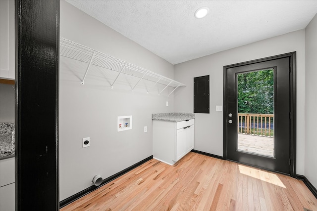 washroom featuring a textured ceiling, baseboards, hookup for a washing machine, and light wood-style floors