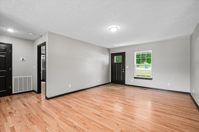 entryway featuring light wood-style floors, baseboards, visible vents, and a textured ceiling