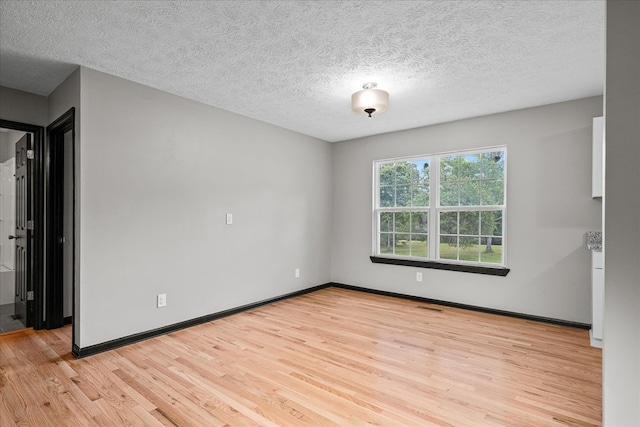 unfurnished room with visible vents, a textured ceiling, light wood-style flooring, and baseboards