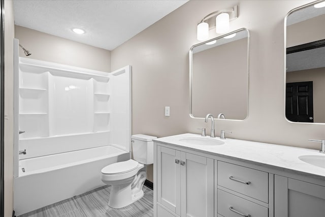 bathroom featuring toilet, a textured ceiling, a sink, and bathing tub / shower combination