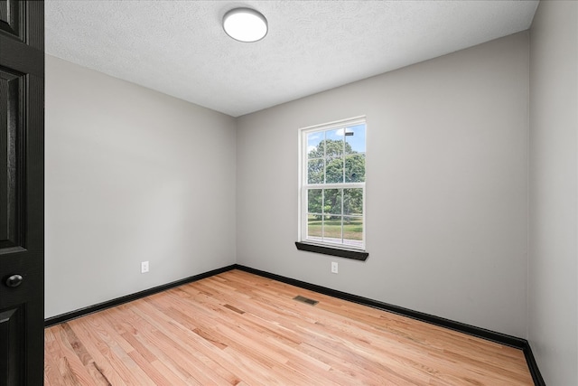 unfurnished room with baseboards, visible vents, a textured ceiling, and light wood finished floors